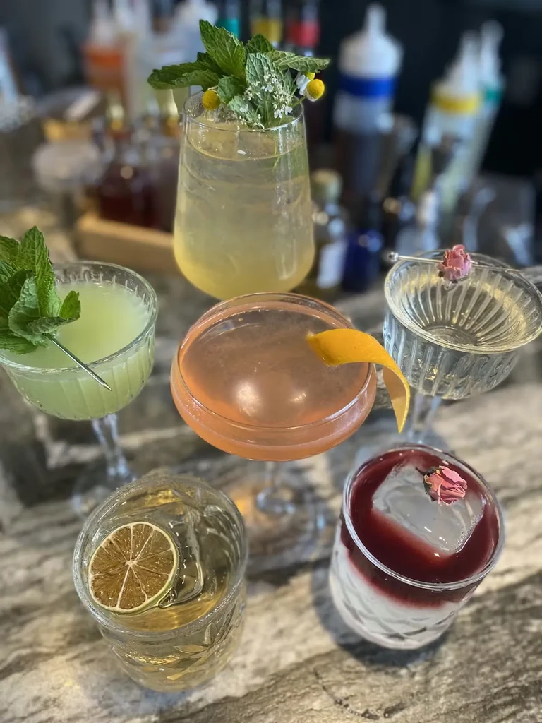Six uniquely garnished cocktails displayed on a marble countertop.