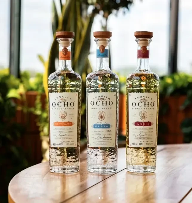 Three Tequila Ocho bottles: Reposado, Plata, Añejo, on wood.