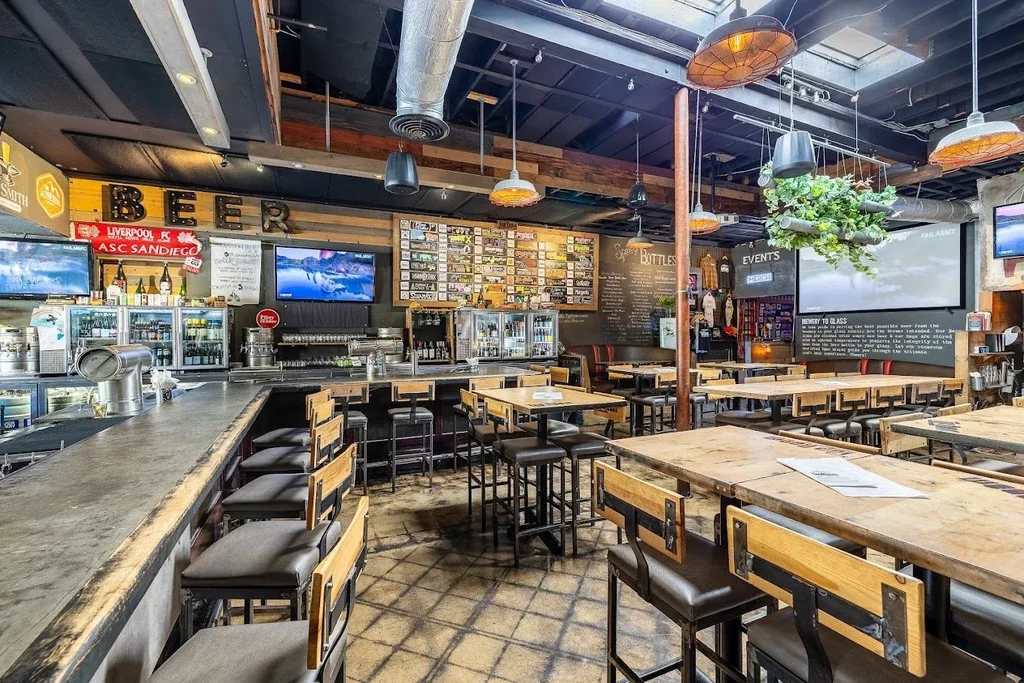 Empty, industrial bar interior with concrete counter and 'BEER' sign.