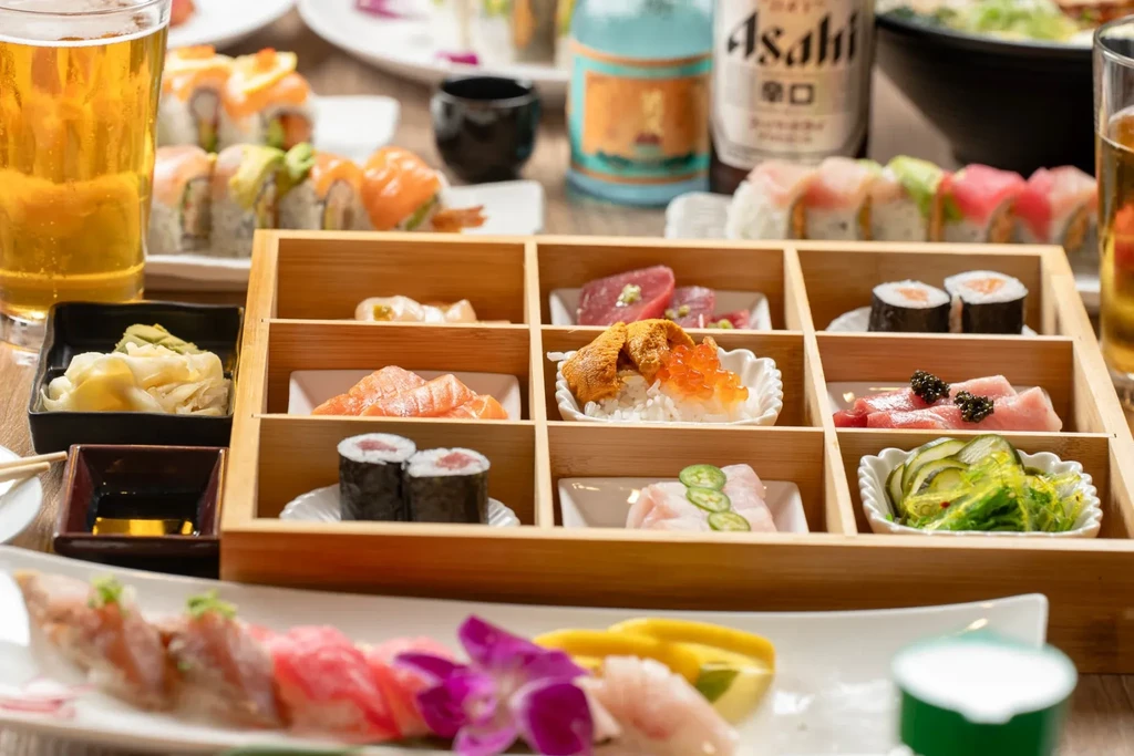 Japanese sushi, sashimi, maki, and bento box on a wooden table.