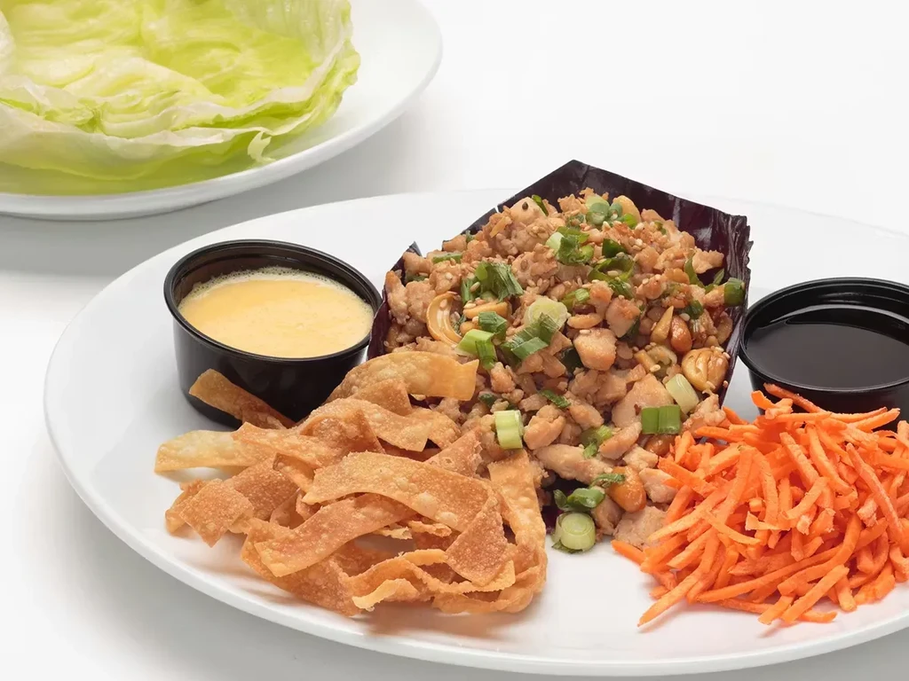 Asian minced chicken lettuce wrap platter with sauces and wontons.