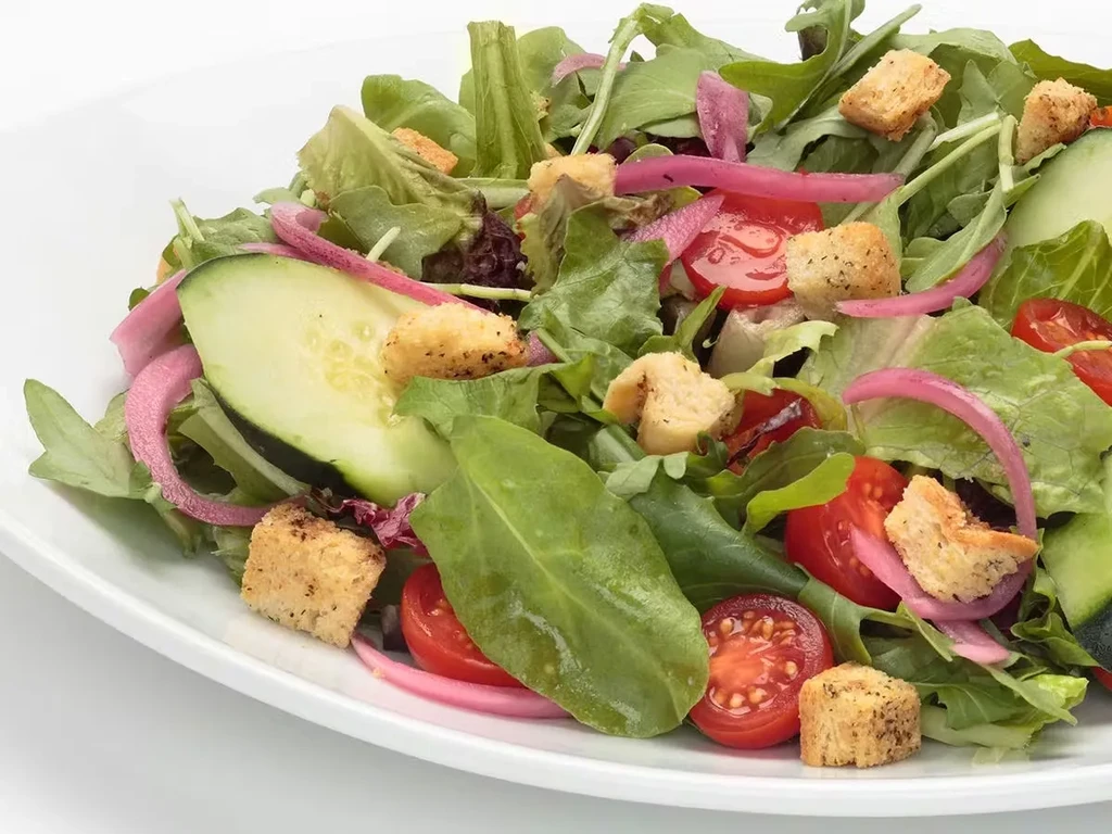 Fresh salad with mixed greens, tomatoes, onions, cucumber, and croutons.