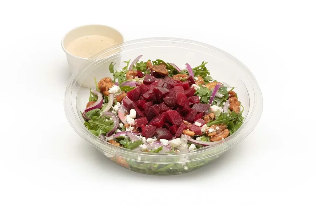 Colorful beet, feta, pecan salad in takeout container with dressing.
