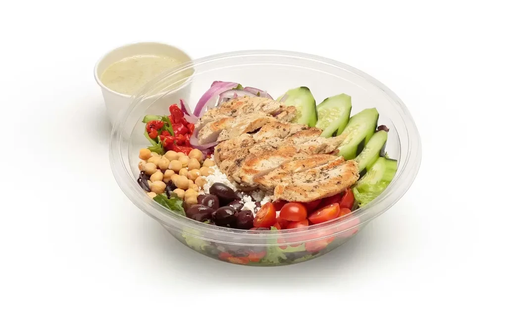 Grilled chicken salad in a takeout bowl with vegetables and dressing.