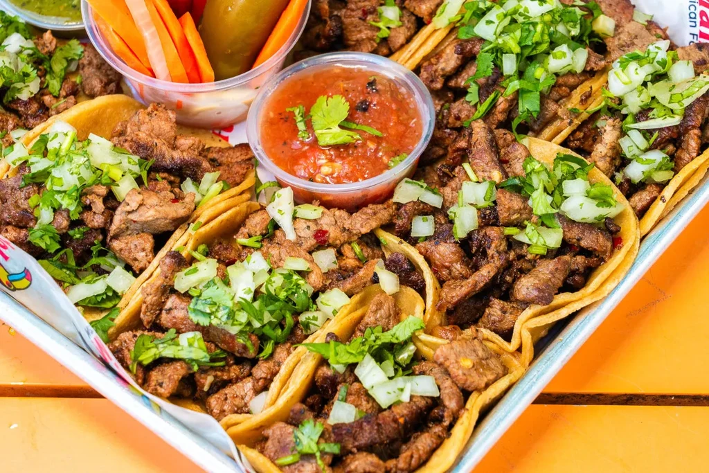Top-down, close-up of meat tacos with onions, cilantro, and salsas.