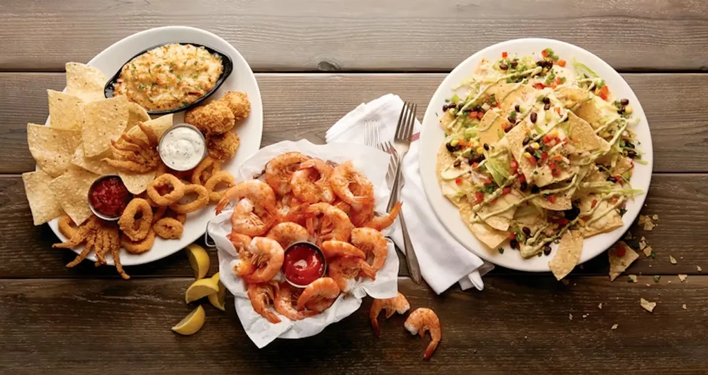 Fried seafood, cooked shrimp, and loaded nachos on a rustic table.