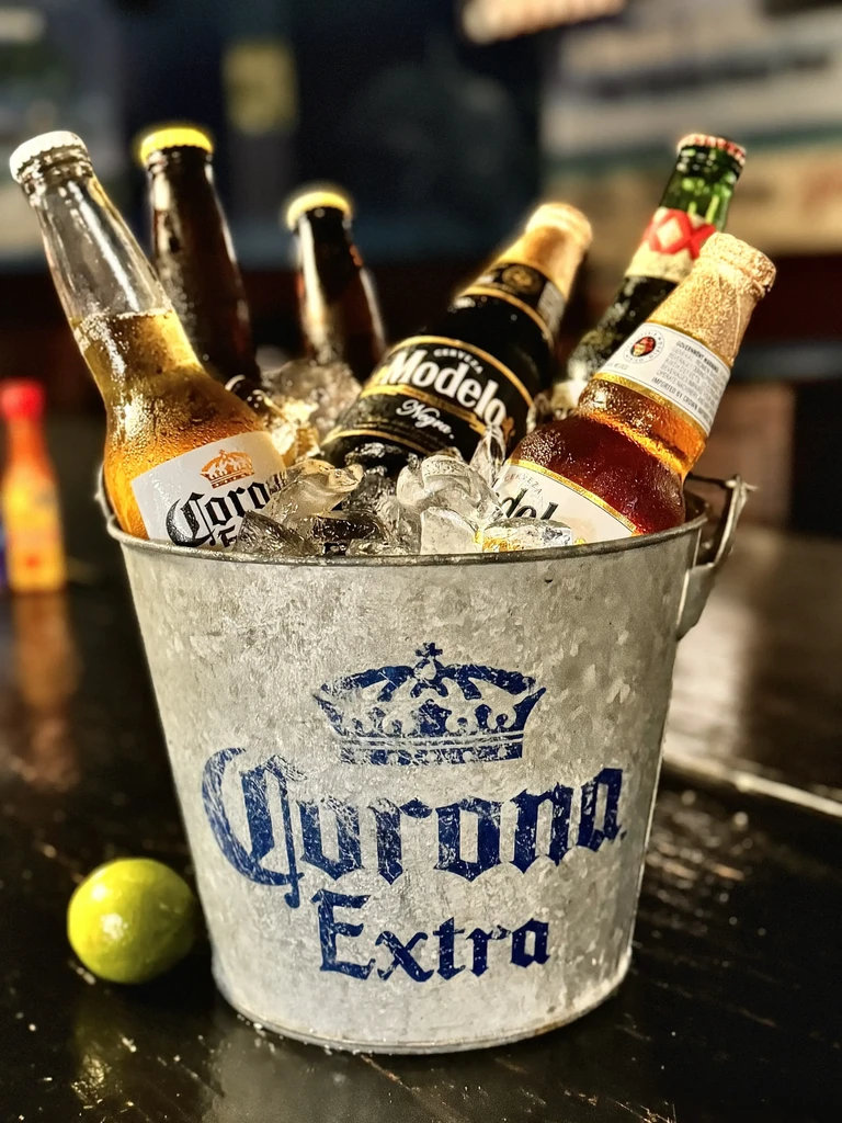 Galvanized Corona bucket with ice, Corona, Modelo beers, and a lime.