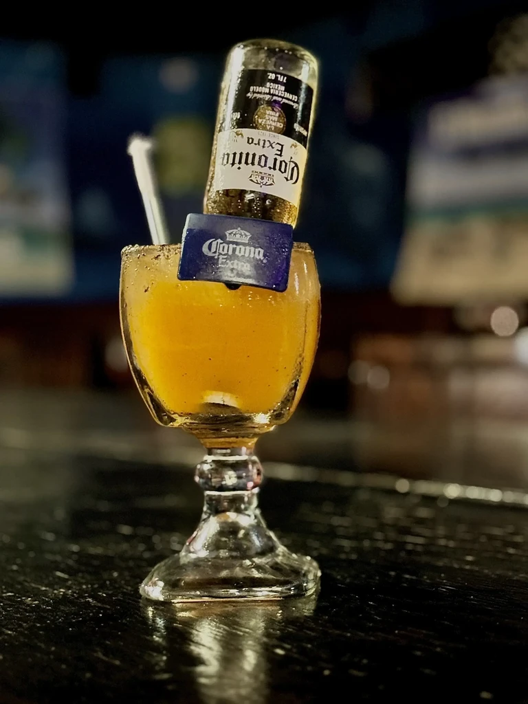 Orange Coronarita cocktail in a stemmed glass with an inverted Corona beer.