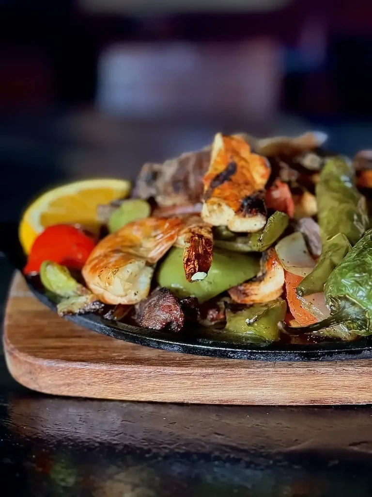 Sizzling shrimp, chicken, and vegetable fajitas in a cast-iron skillet.
