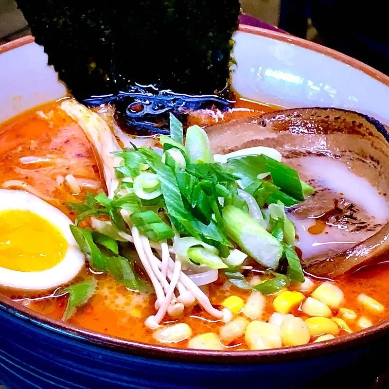 Close-up top-down ramen with pork, egg, nori, mushrooms, green onions.