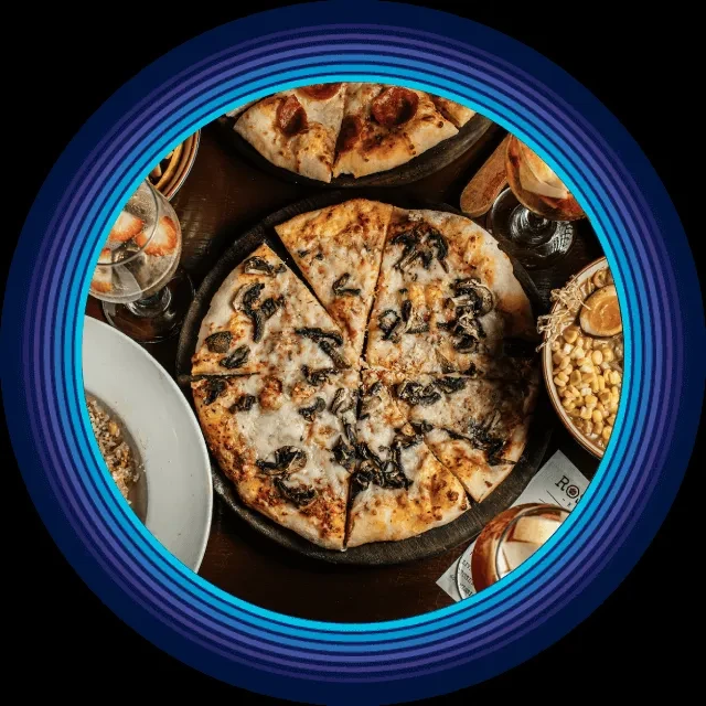 Overhead shot of a restaurant table with pizzas, drinks, and dishes.