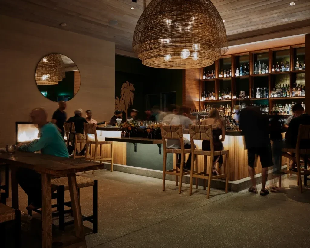 Warm contemporary bar interior at night, well-stocked shelves, blurred patrons.