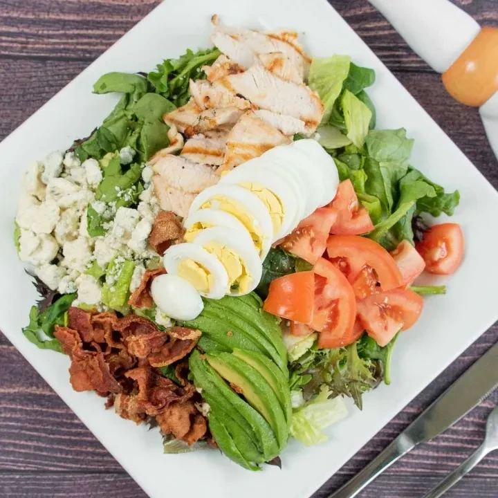 Vibrant Cobb salad with chicken, avocado, bacon, eggs, and blue cheese.