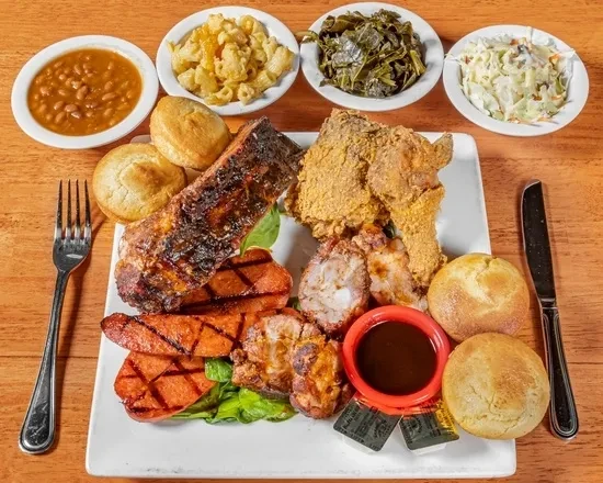 Platter of barbecue ribs, fried chicken, sausage, and four side dishes.
