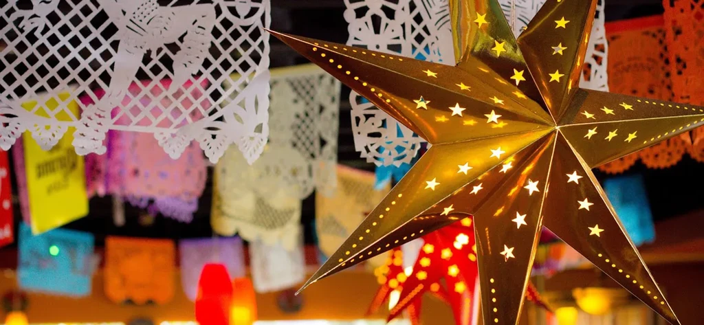 Golden star lantern illuminates colorful Mexican papel picado banners.