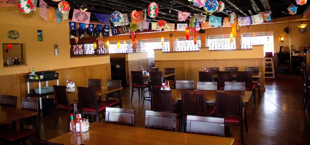 Colorful Mexican restaurant interior with papel picado and wooden furniture.
