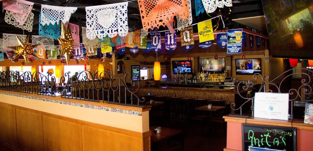 Festive Mexican restaurant interior with papel picado, a bar, and TVs.