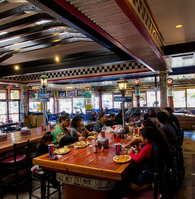 Busy, retro roadside diner interior with people eating.