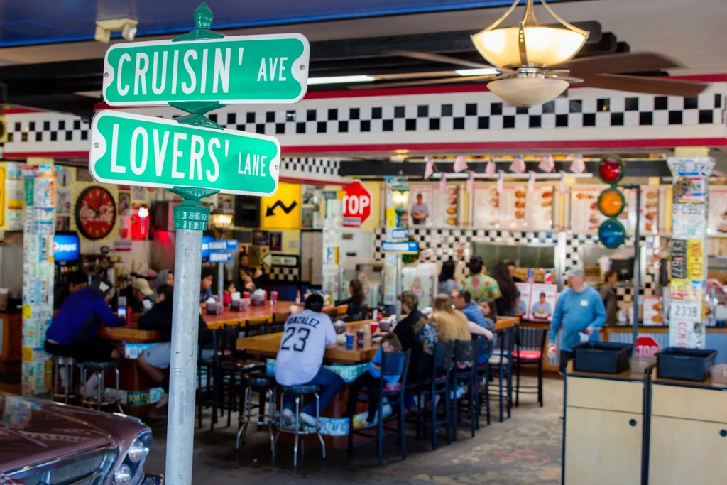 Busy retro diner interior with Cruisin' Ave and Lovers' Lane signs.