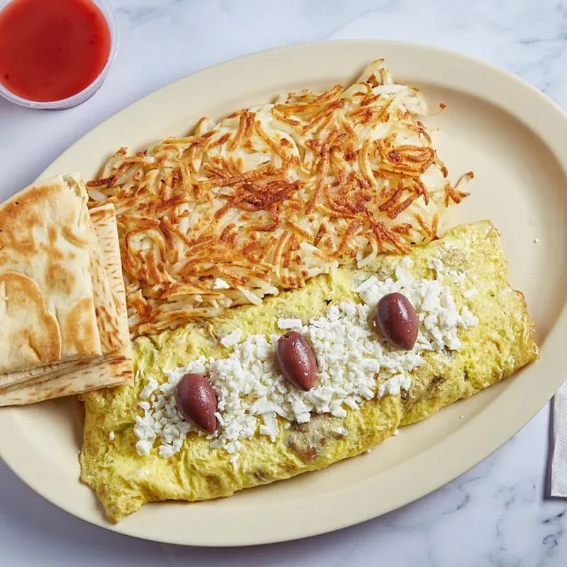 Omelet with feta, olives, hash browns, pita bread, and red sauce.