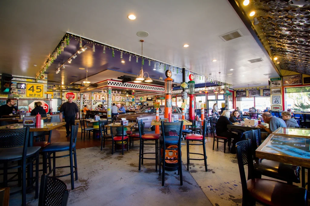 Lively retro diner decorated with vintage automotive memorabilia and classic car.