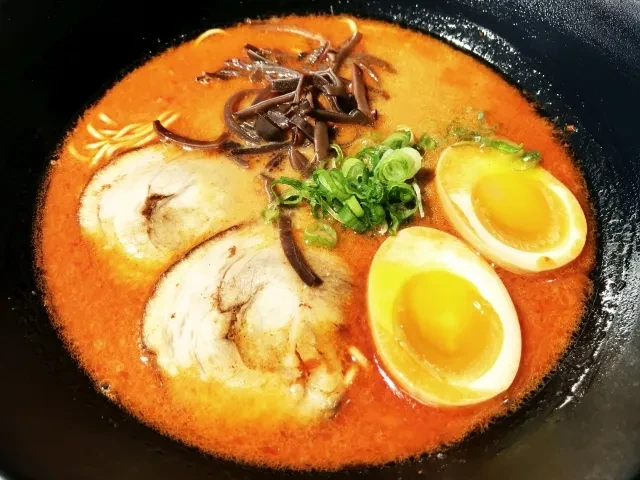 Overhead shot of spicy ramen with chashu, eggs, mushrooms, and green onions.