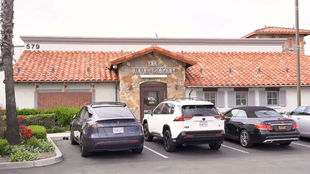 The Mining Company restaurant exterior: orange roof, stone facade, parked cars.