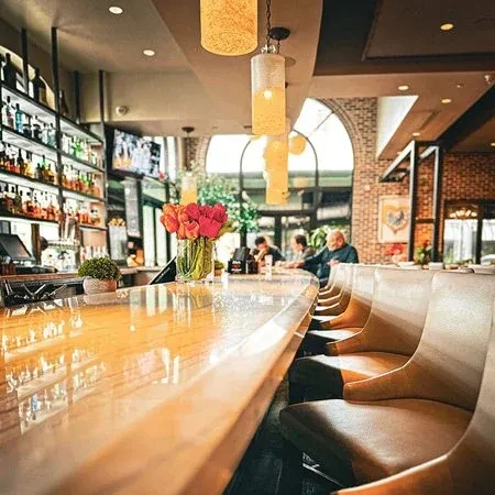 Polished wooden bar, red tulips, liquor shelf, and indistinct patrons.