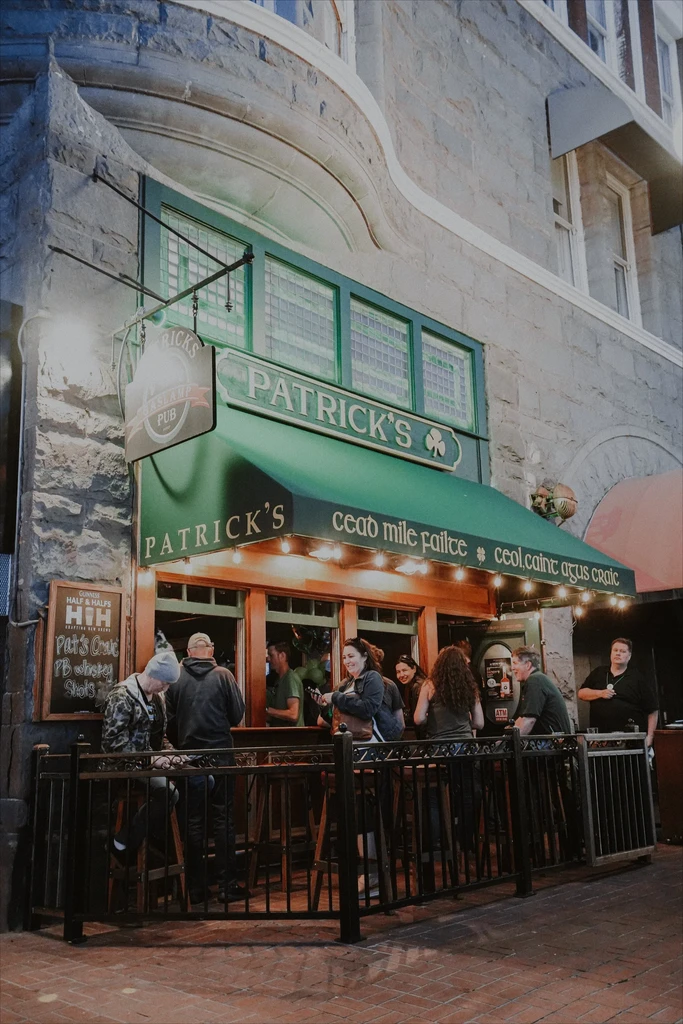Illuminated Patrick's Irish pub exterior at dusk with patrons.