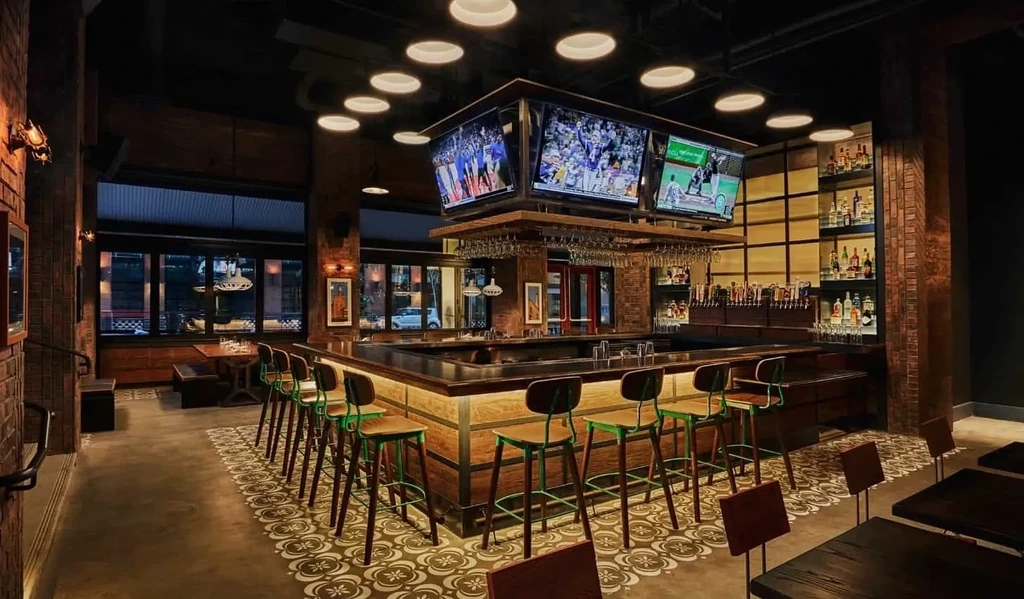 Modern bar interior featuring a large counter and multiple sports screens.