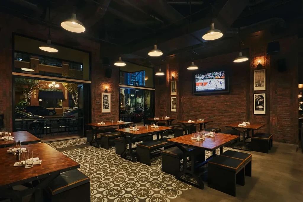 Dark, rustic industrial restaurant with brick walls and patterned floor.