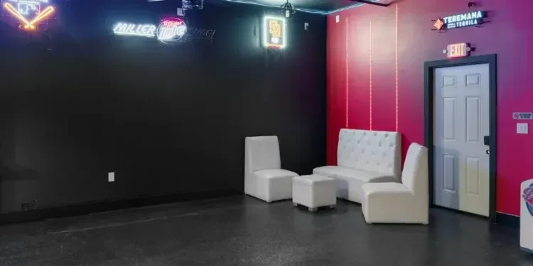 Lounge with dark and magenta walls, white furniture, and bright neon signs.