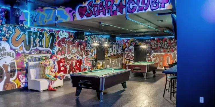 Two pool tables, graffiti walls, blue lights, and a jester mannequin.