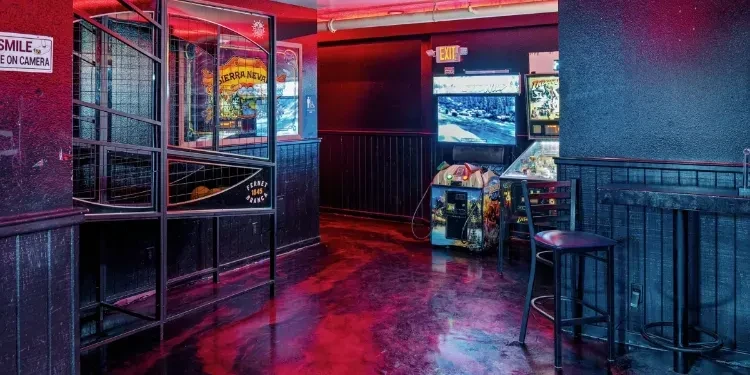 Red and blue lit arcade bar with games and reflective floor.