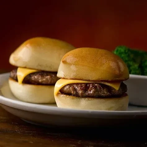 Two mini cheeseburger sliders with melted cheese on an oblong plate.