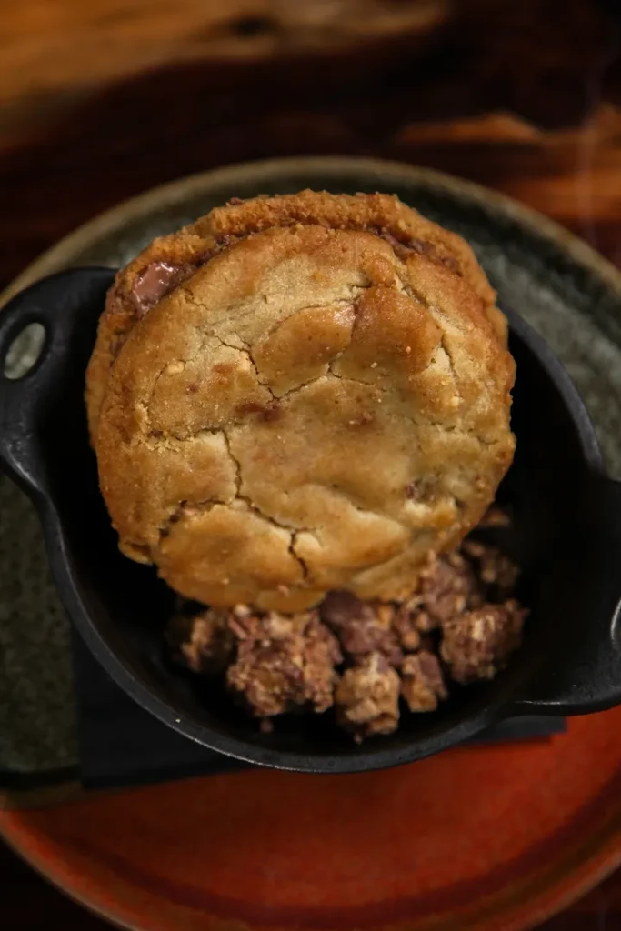 Golden sandwich cookie in a cast iron dish with chocolate crumble.