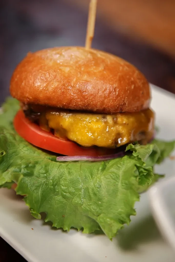 Cheeseburger with toasted bun, melted cheese, tomato, onion, and lettuce.