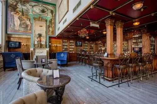 Ornate, luxurious bar lounge with seating, fireplace, and well-stocked bar.