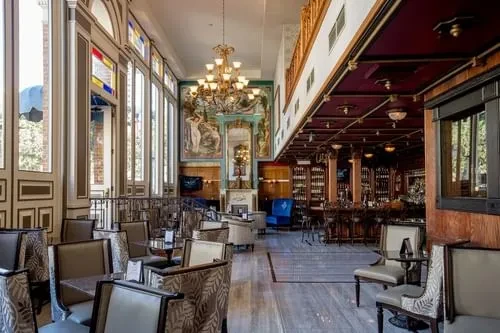 Ornate, empty restaurant and bar interior with chandelier and mural.
