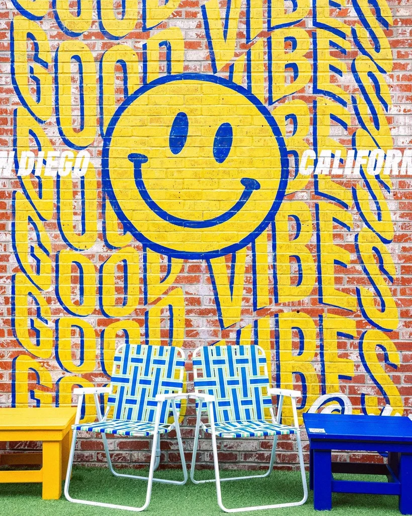 "GOOD VIBES" San Diego mural with smiley face, lounge chairs, and tables.