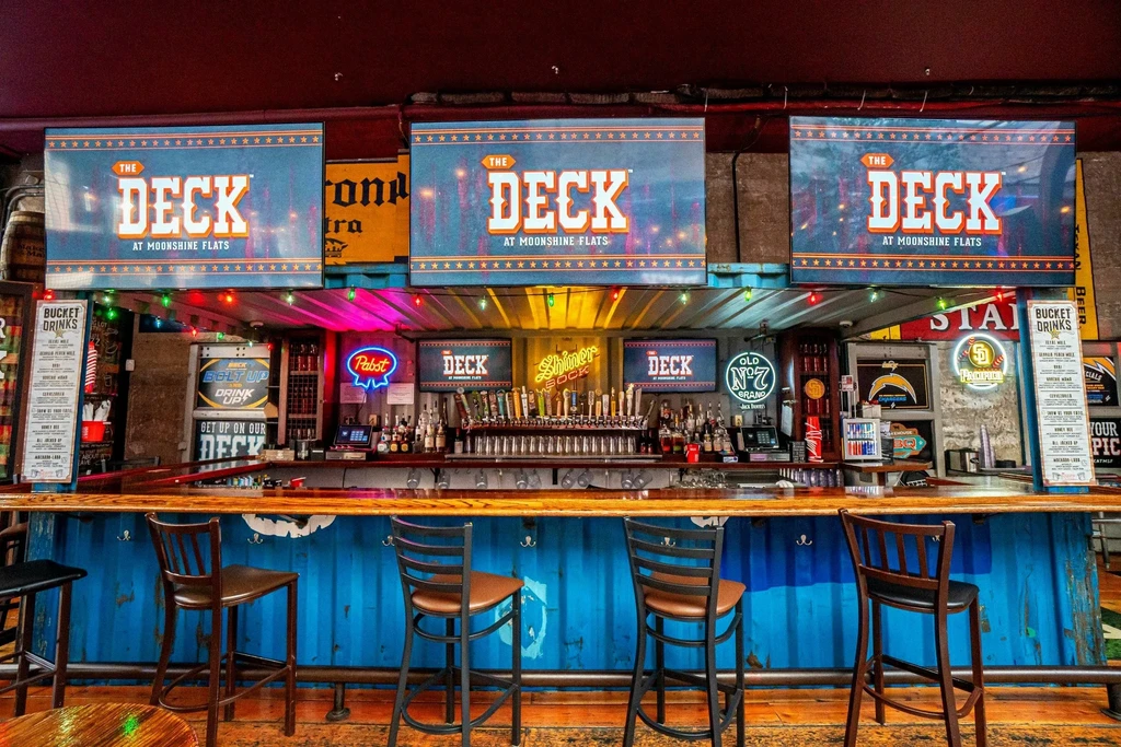 Heavily branded bar with neon signs, beer taps, and metal counter.