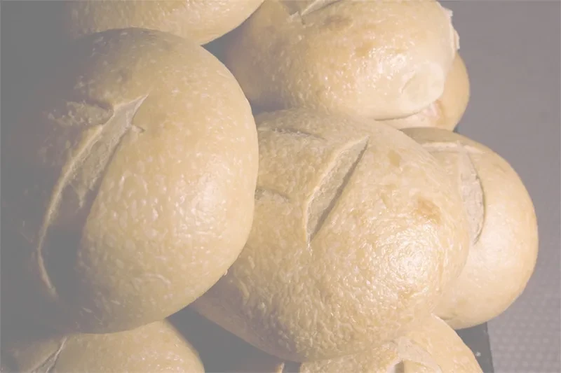 Close-up of piled pale bread rolls with score marks.
