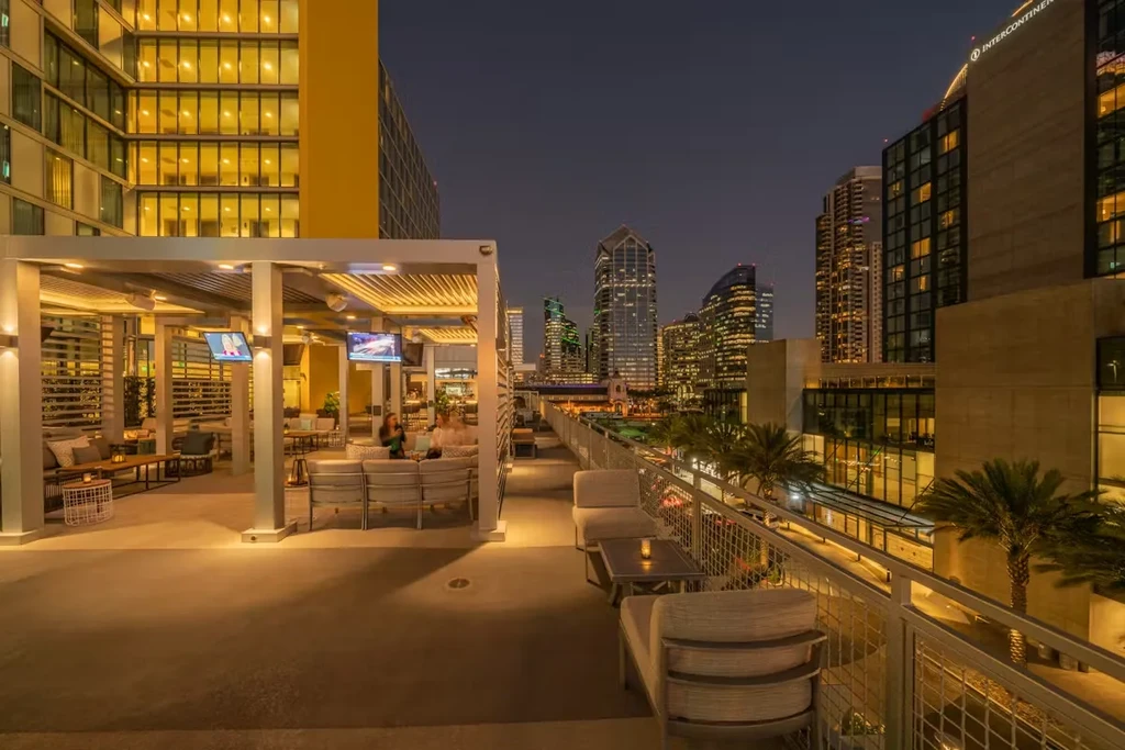 Modern rooftop lounge with warm lighting and city skyline at dusk.