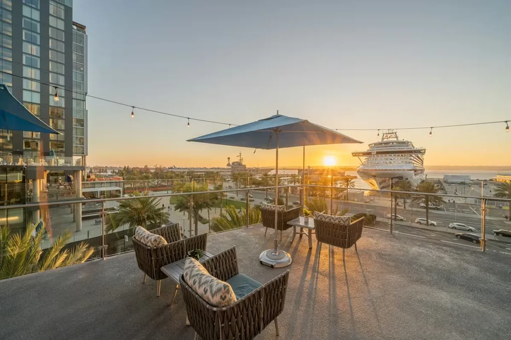Outdoor patio at sunset overlooking a harbor with a cruise ship.