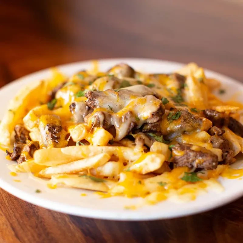 French fries loaded with melted cheese, steak, and herbs.