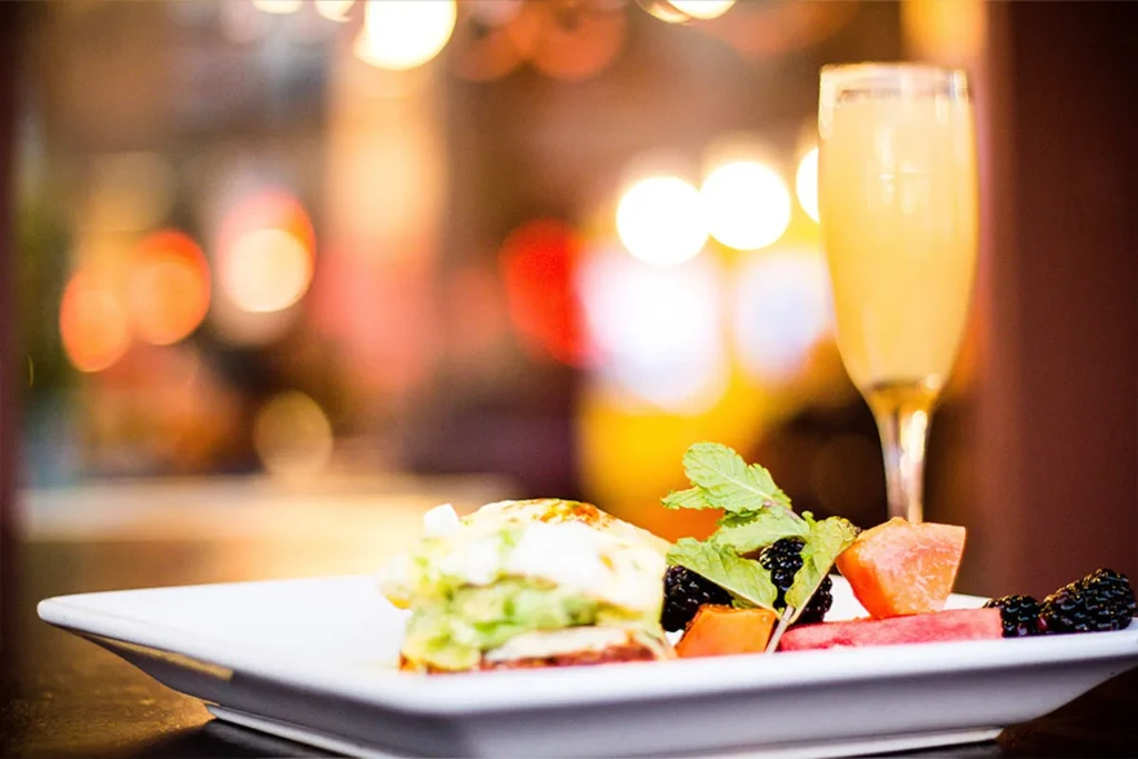 A savory dish with fruit and mint, next to a mimosa.