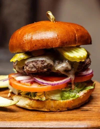 Cheeseburger with melted cheese, beef patty, brioche bun, and fresh vegetables.