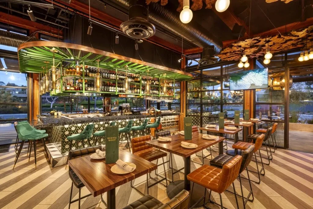 Stylish restaurant interior featuring prominent green bar, geometric tiles, and unique lights.