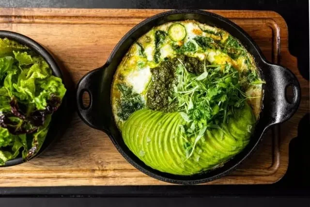 Cast-iron skillet frittata with avocado, pesto, microgreens, and side salad.