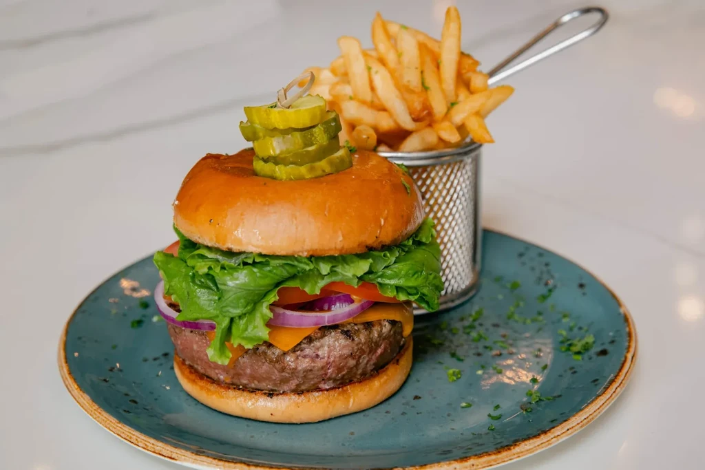 Gourmet hamburger with golden fries on a dark teal plate.